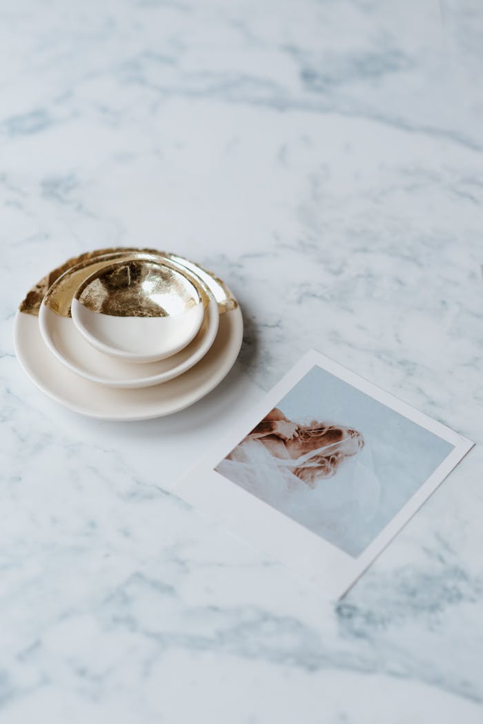 From above of collection of saucers with shiny ornament near photography of bride on marble table
